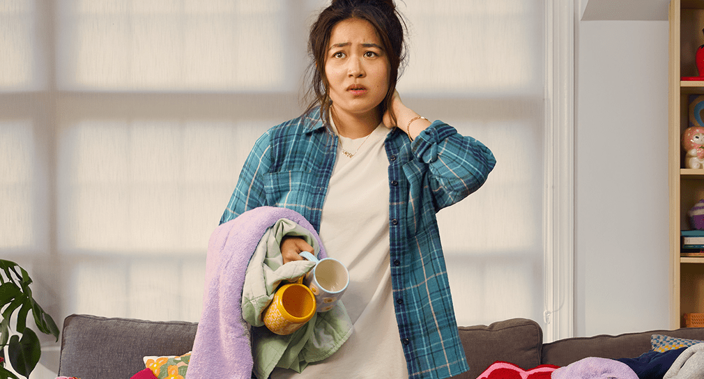 An anxious-looking young woman holds a basket of unfolded laundry.
