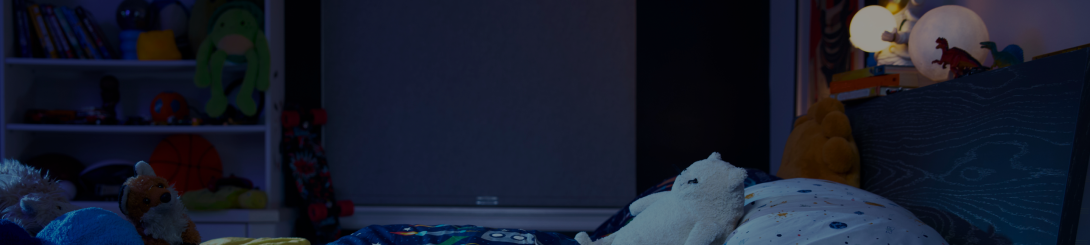 A child's bedroom at night with stuffed animals on the bed.