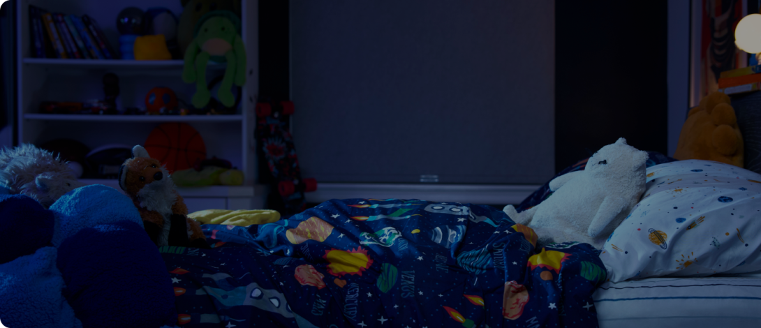 A child's bedroom at night with stuffed animals on the bed.