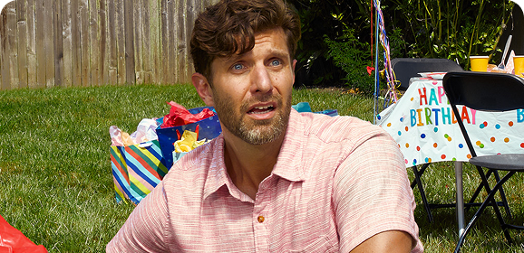 A man has a panicked expression while struggling to inflate a bouncy house.